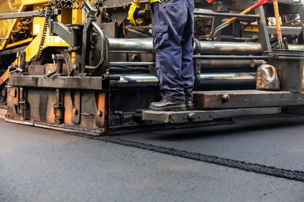 Paving crew operating an asphalt machine before parking lot striping